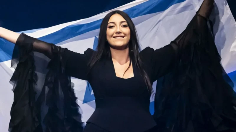 Yuval Raphael mengibarkan bendera Israel dalam kontes lagu Eurovision tahun ini di Swiss. Partisipasi negara tersebut di edisi 2026 kini menuai ancaman boikot dari Irlandia dan beberapa negara lain. (Sumber: EPA)